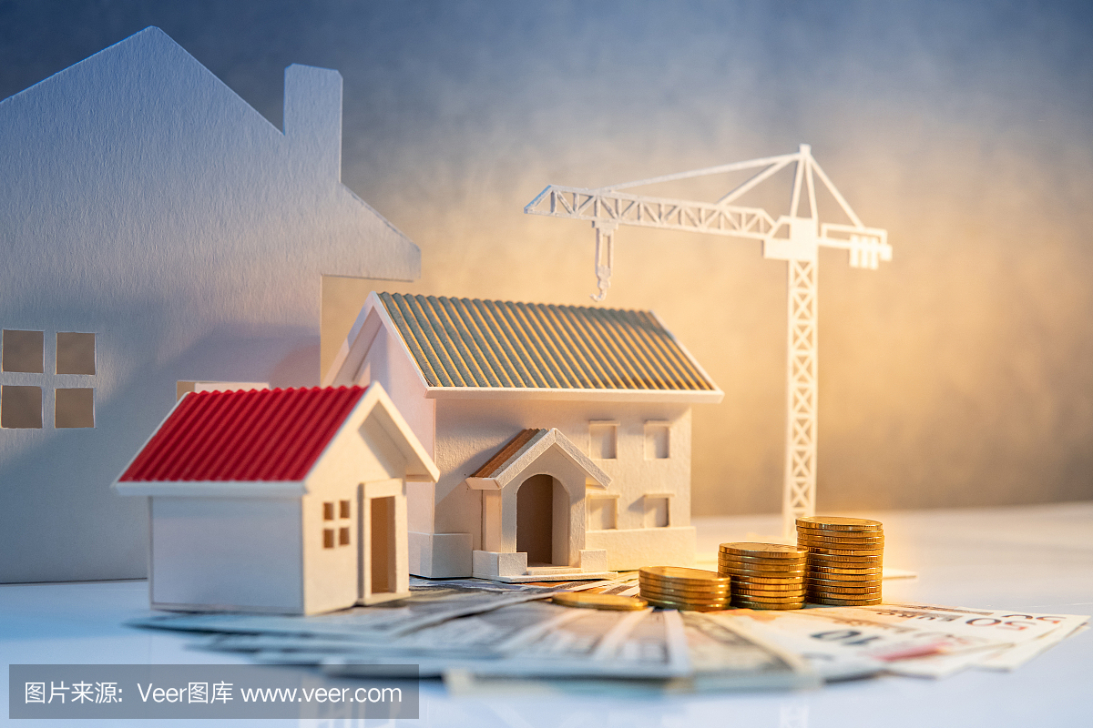 房地產(chǎn)或房地產(chǎn)開發(fā)。建設(shè)企業(yè)投資理念。住房抵押貸款利率。國際鈔票硬幣堆,桌子上有房屋和建筑起重機模型。